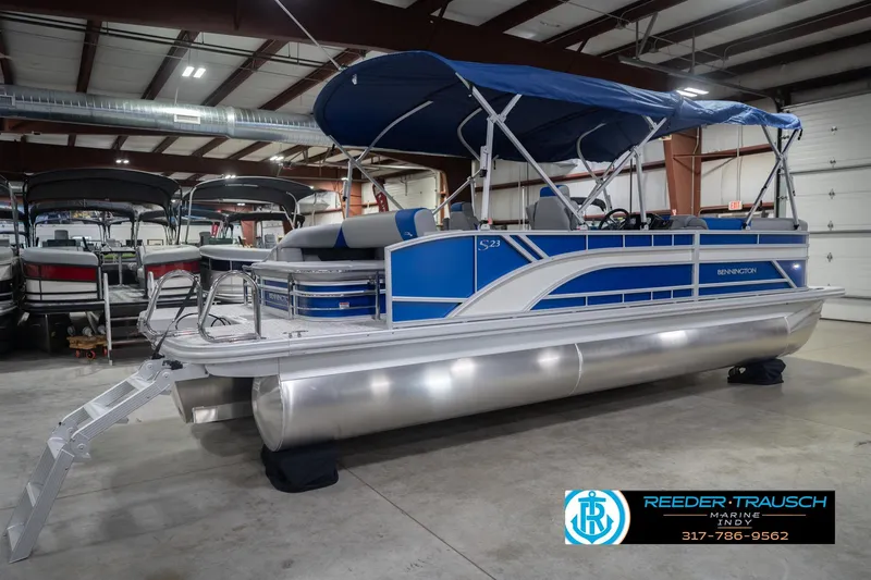 Slide: The Image of 2026 Bennington 23 SSB pontoon boat with blue canopy in indoor showroom. - 8