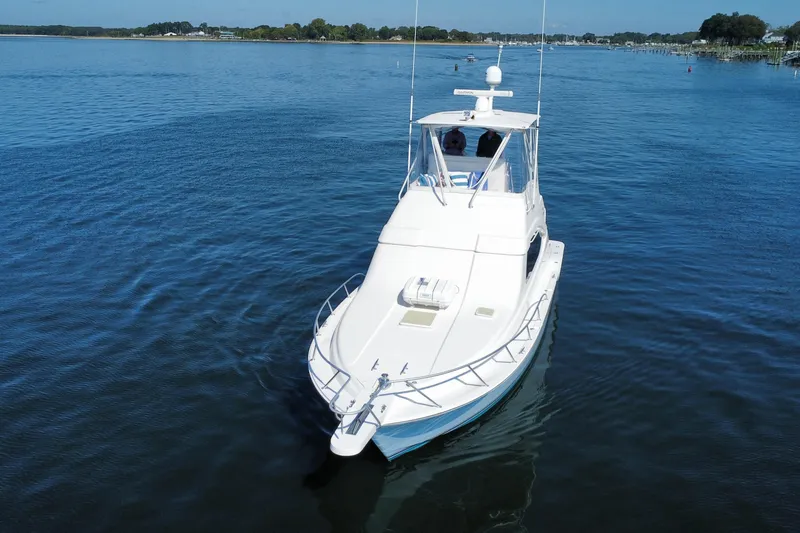 Slide: The Image of 2006 Bertram 390 Convertible yacht on calm water near a scenic shoreline. - 2