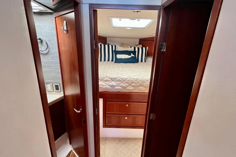 Slide: The Image of Open wooden cabinet in 2006 Bertram 390 Convertible, storing dishes and kitchen items. - 32