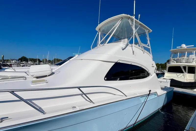 Slide: The Image of 2006 Bertram 390 Convertible yacht docked, showcasing sleek design and ladder access. - 6