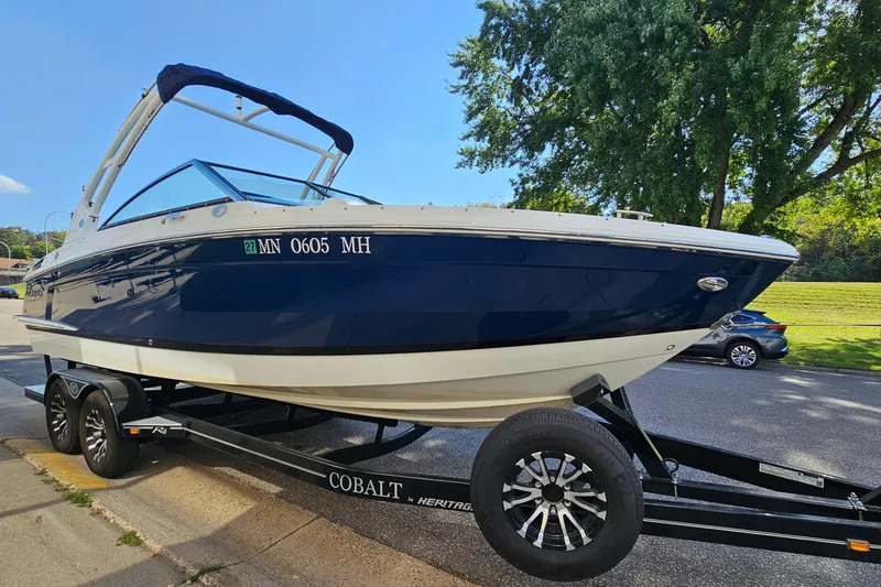 Slide: The Image of 2022 Cobalt R4 boat on trailer, parked on street, surrounded by trees. - 3