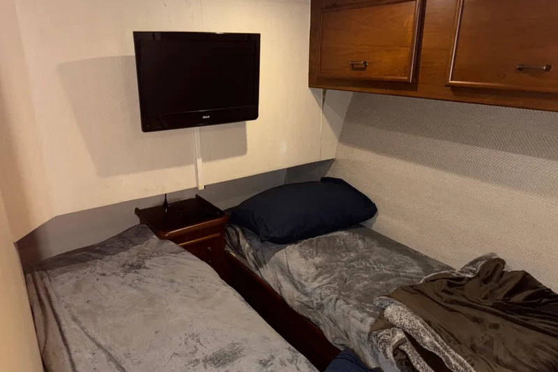 Slide: The Image of 1988 Ocean Convertible cabin with twin beds, wall-mounted TV, and wooden storage cabinets. - 11
