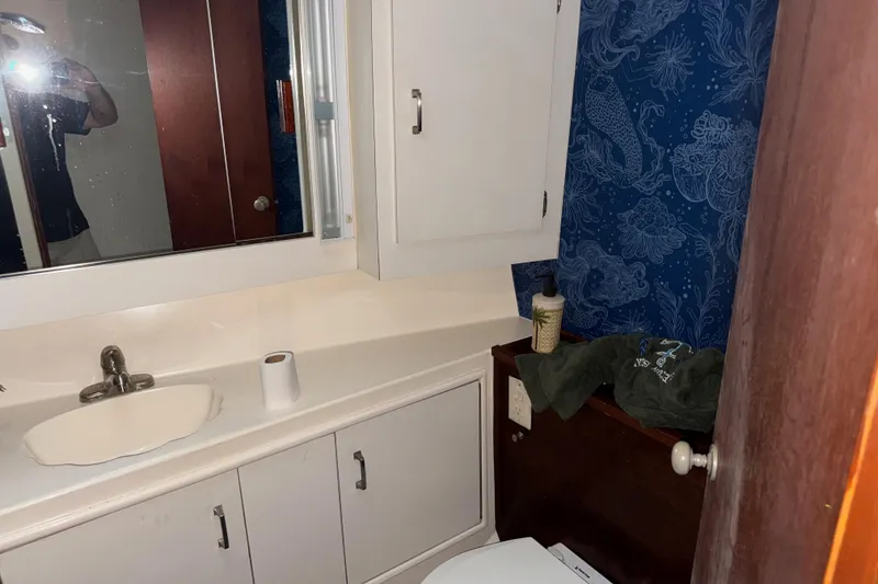 Slide: The Image of Bathroom interior with blue floral wallpaper, white cabinets, and a sink in an Ocean Convertible 1988. - 13