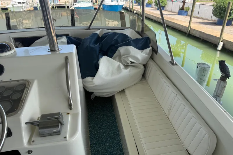 Slide: The Image of 1988 Ocean Convertible boat interior with white seating, docked near calm water. - 7