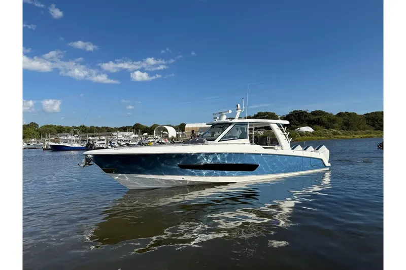 Slide: The Image of 2024 Boston Whaler 420 Outrage boat on calm water under clear blue sky. - 2