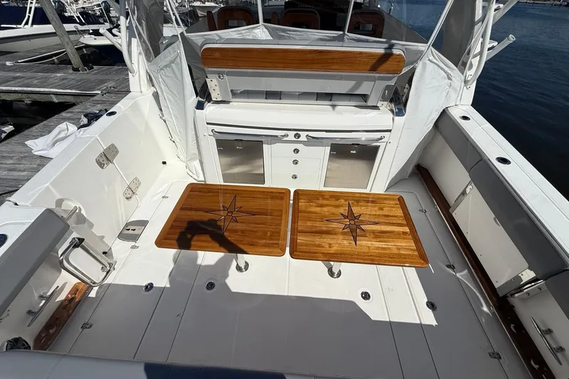 Slide: The Image of 2024 Boston Whaler 420 Outrage boat interior with wooden tables and seating area. - 20