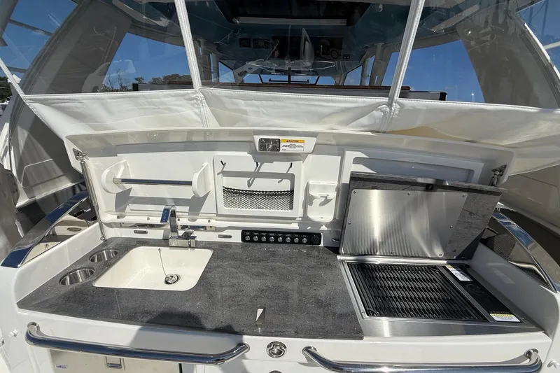 Slide: The Image of 2024 Boston Whaler 420 Outrage boat kitchen with sink, grill, and storage. - 25