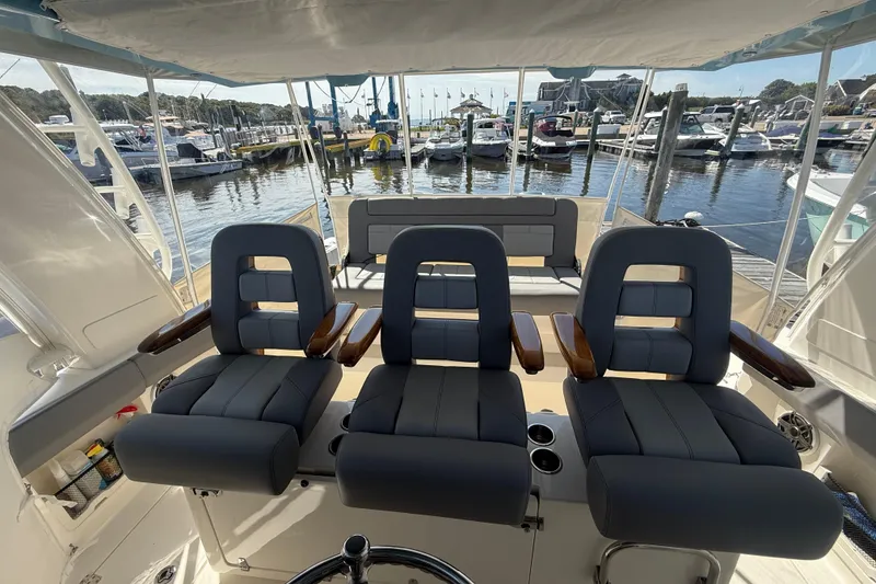 Slide: The Image of 2024 Boston Whaler 420 Outrage cockpit with three cushioned seats, docked at marina. - 28