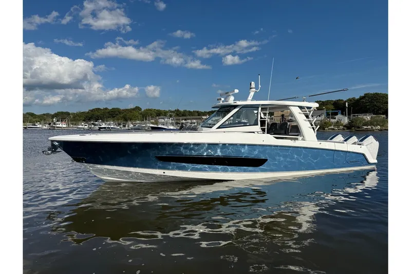Slide: The Image of 2024 Boston Whaler 420 Outrage boat on calm water under a clear blue sky. - 3