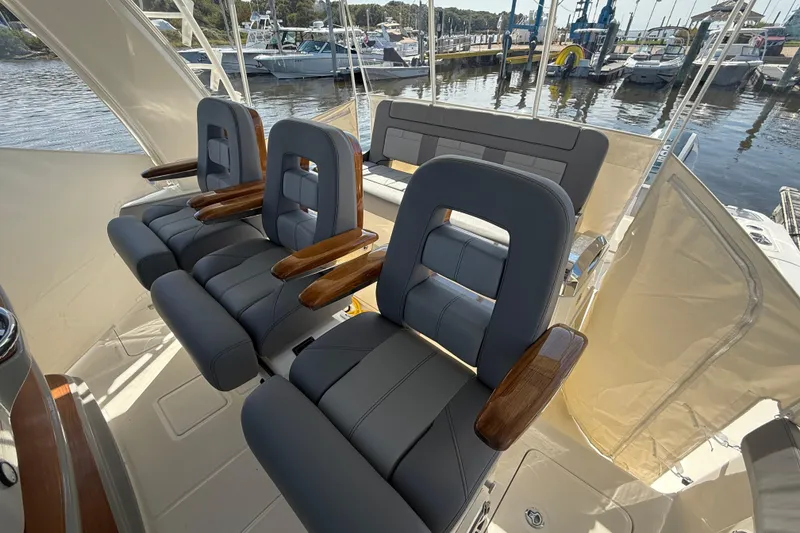 Slide: The Image of 2024 Boston Whaler 420 Outrage helm seats with wooden armrests, docked at marina. - 31
