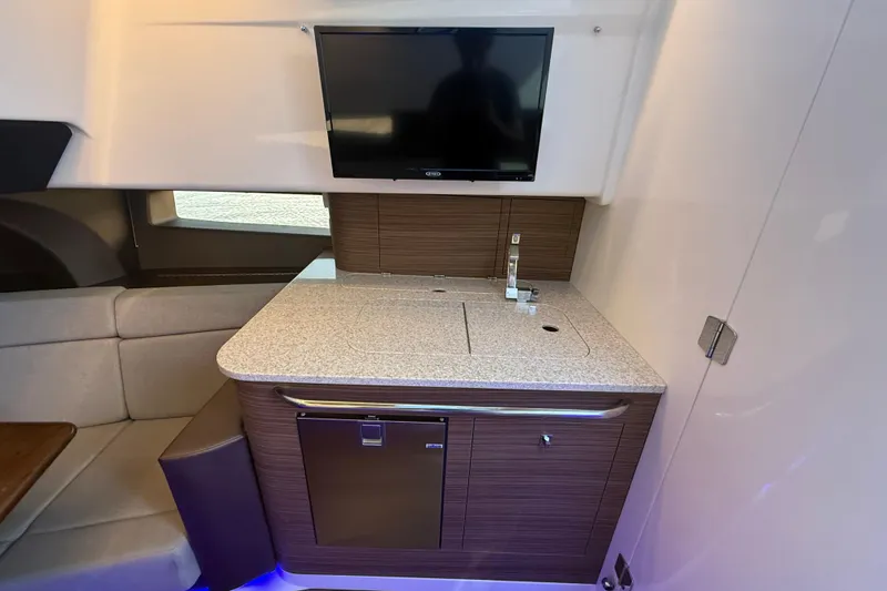 Slide: The Image of 2024 Boston Whaler 420 Outrage interior with kitchenette, TV, and seating area. - 39