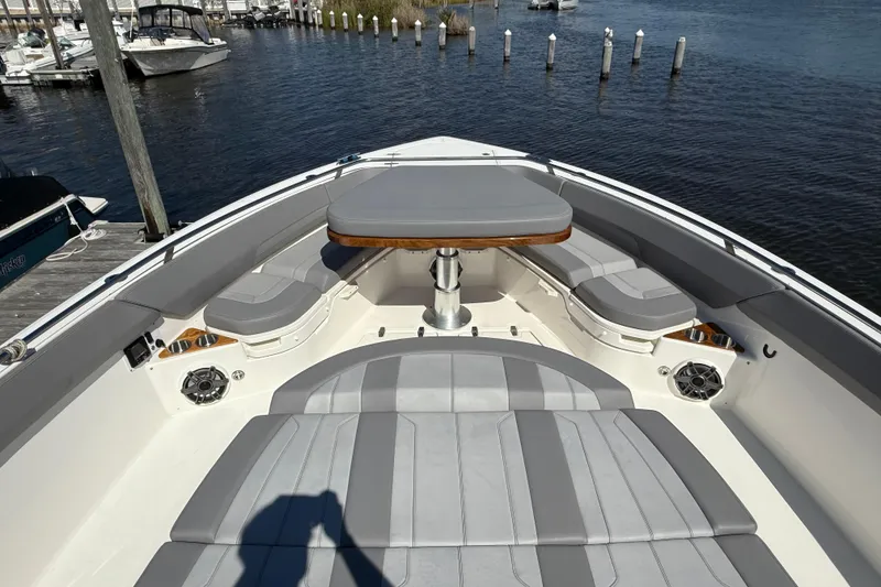 Slide: The Image of 2024 Boston Whaler 420 Outrage boat interior with cushioned seating and table on the water. - 46