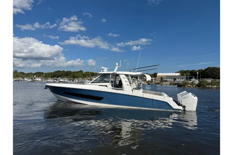 Slide: The Image of 2024 Boston Whaler 420 Outrage boat on calm water under a clear blue sky. - 54