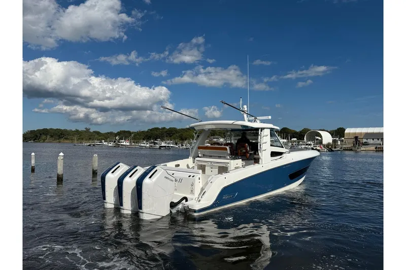 Slide: The Image of 2024 Boston Whaler 420 Outrage boat on water, featuring triple engines, under a clear blue sky. - 6