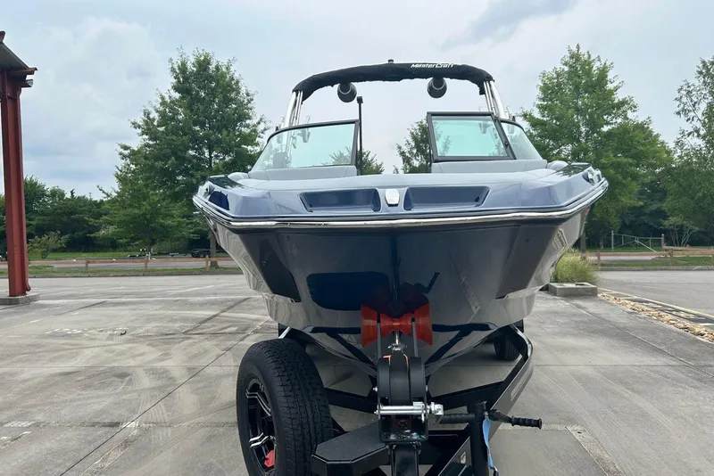 Slide: The Image of 2025 MasterCraft NXT23 boat on trailer, parked outdoors, showcasing sleek design and modern features. - 3