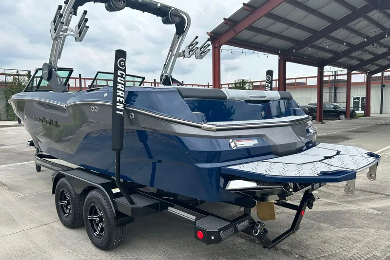Slide: The Image of 2025 MasterCraft NXT23 boat on trailer, blue exterior, parked under a metal canopy. - 4