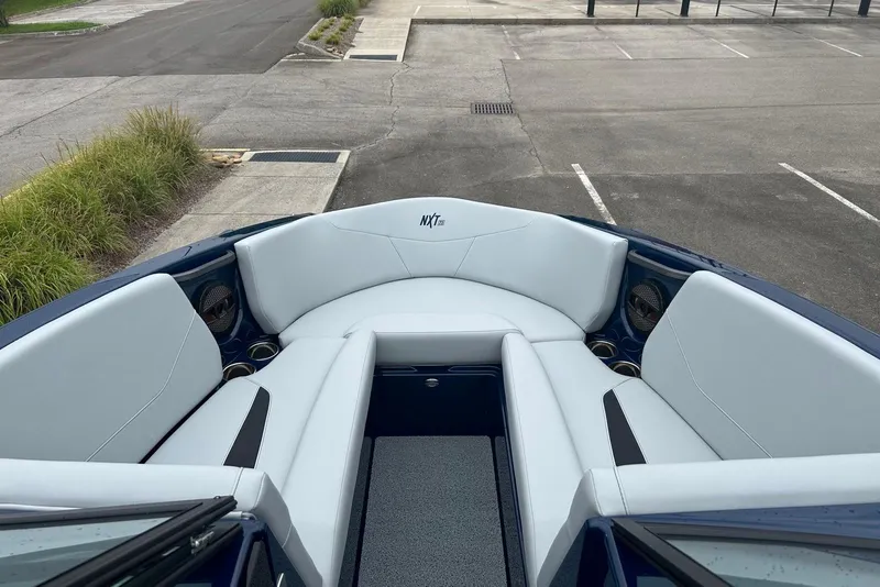 Slide: The Image of 2025 MasterCraft NXT23 boat interior with white seating and cup holders. - 7