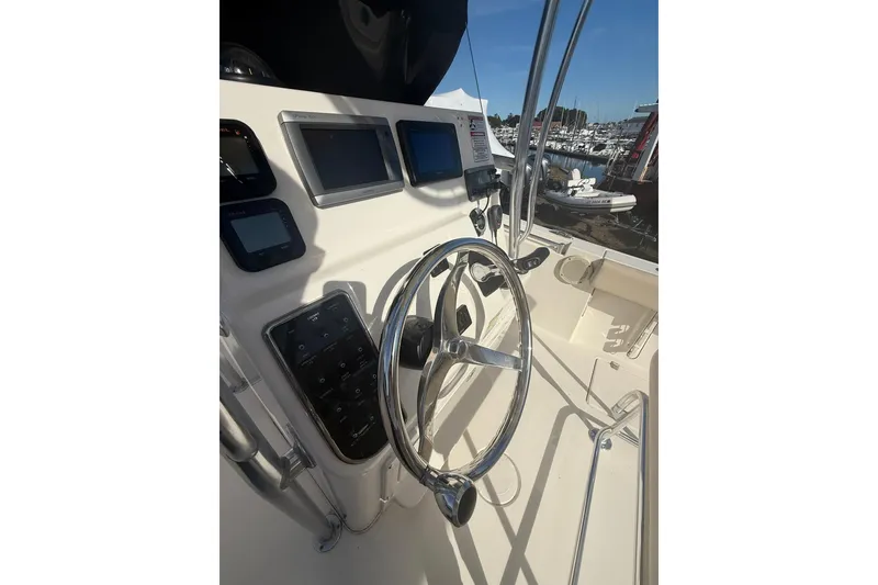 Slide: The Image of 2013 Cobia 237 Center Console boat dashboard with steering wheel and navigation screens. - 10