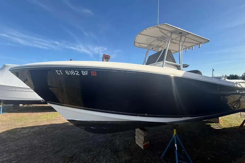 Slide: The Image of 2013 Cobia 237 Center Console boat on stands under clear blue sky. - 3