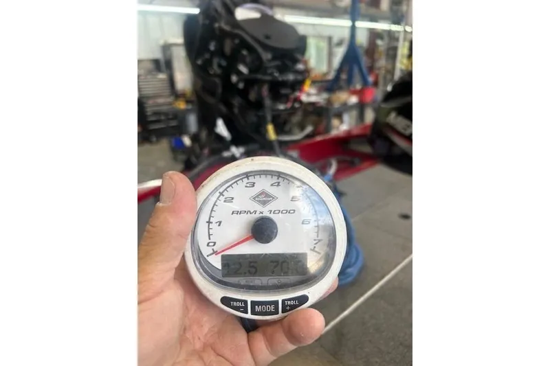 Slide: The Image of Hand holding a tachometer in a workshop, Tracker Pro 170, 2025 model. - 12