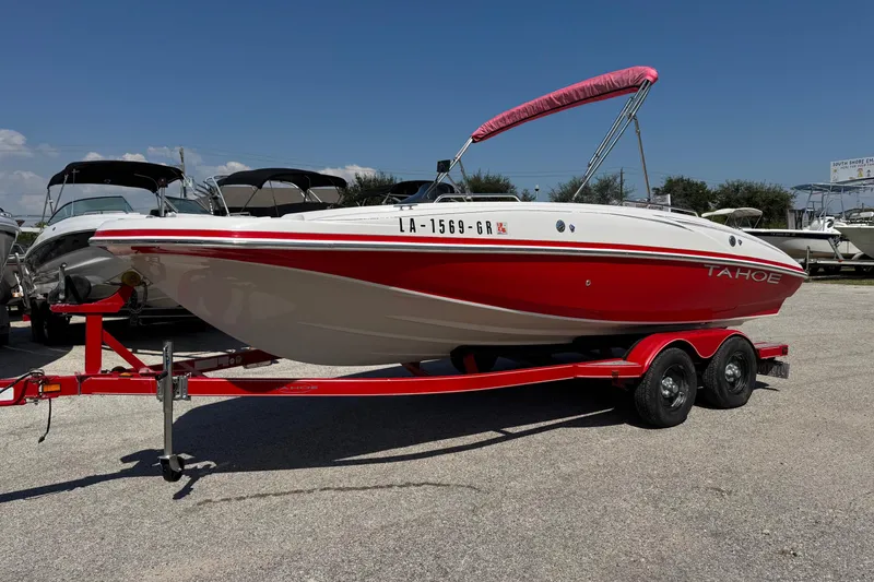 Slide: The Image of 2008 Tahoe 195 boat with red and white design on a trailer in a marina. - 1