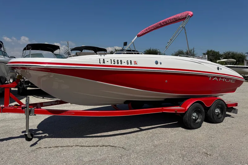 Slide: The Image of 2008 Tahoe 195 boat in red and white on a trailer, sunny day background. - 2