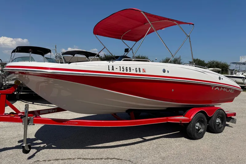 Slide: The Image of 2008 Tahoe 195 boat with red and white design, parked on a trailer under a clear sky. - 22