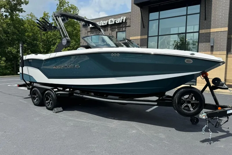 The Image of 2025 MasterCraft NXT24 boat on trailer, parked outside dealership. - 1