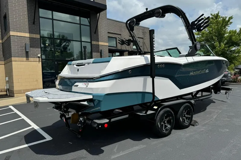 Slide: The Image of 2025 MasterCraft NXT24 boat on trailer, parked outside modern building. - 3