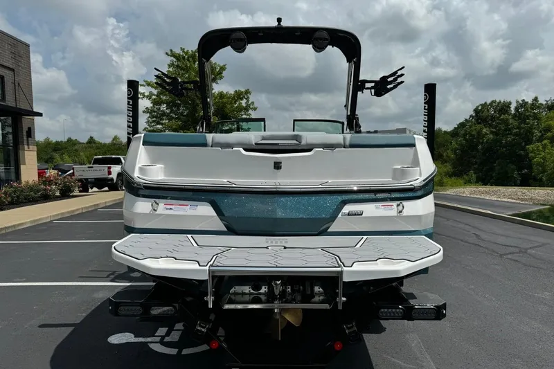 Slide: The Image of 2025 MasterCraft NXT24 boat, rear view, parked outdoors under cloudy sky. - 4