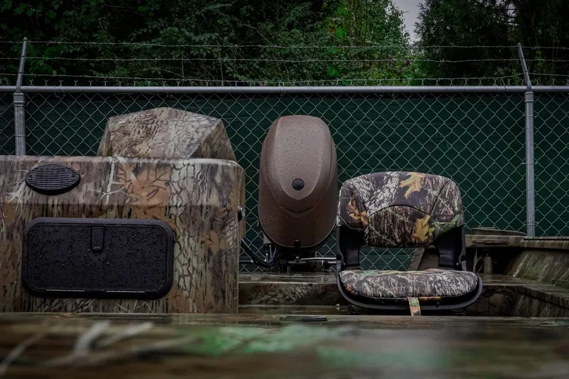 Slide: The Image of Camouflage boat interior with seating, G3 17SC model, 2026, against a chain-link fence backdrop. - 11