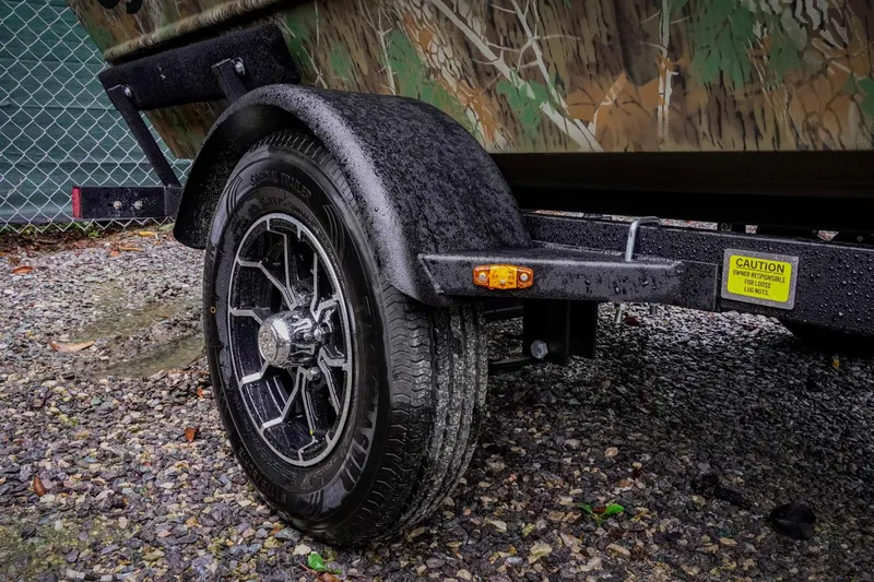 Slide: The Image of Trailer wheel of 2026 G3 17SC boat on gravel, featuring camouflage design. - 29