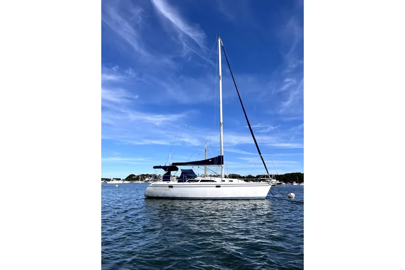 Slide: The Image of 2003 Catalina 320 sailboat on calm water under a clear blue sky. - 1