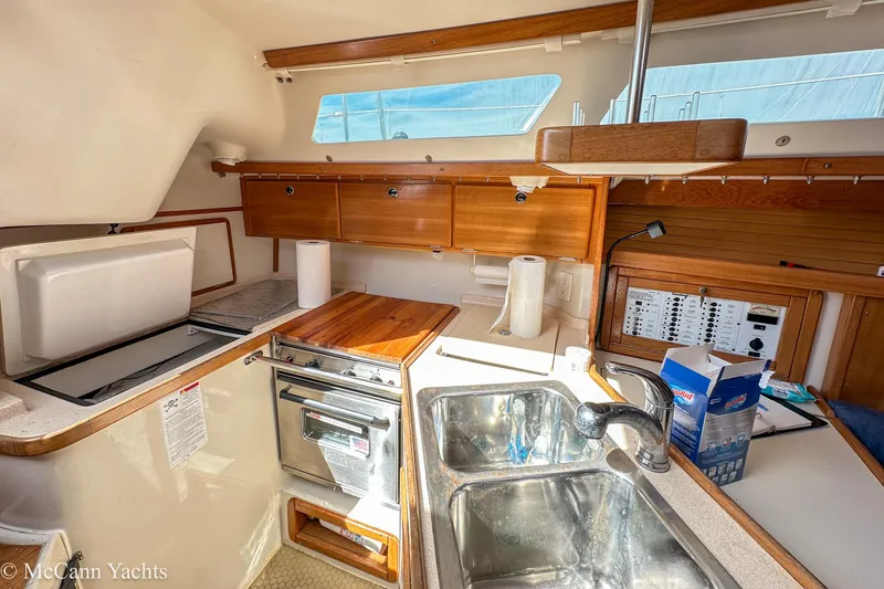 Slide: The Image of 2003 Catalina 320 yacht kitchen with stove, sink, and wooden cabinetry. - 15