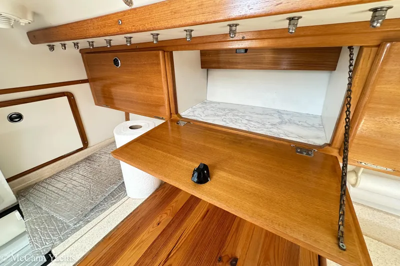 Slide: The Image of Wooden cabinetry in a 2003 Catalina 320 yacht interior, featuring open storage and paper towel holder. - 17