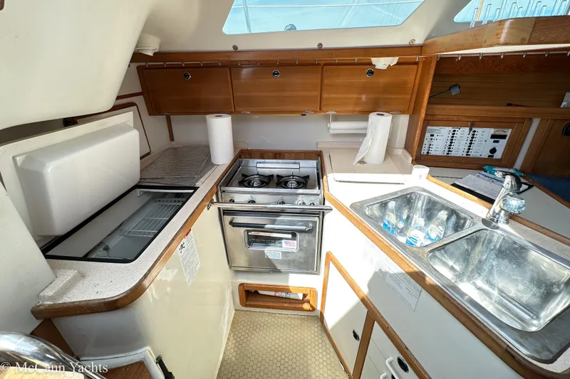 Slide: The Image of 2003 Catalina 320 yacht kitchen with stove, sink, and storage cabinets. - 19