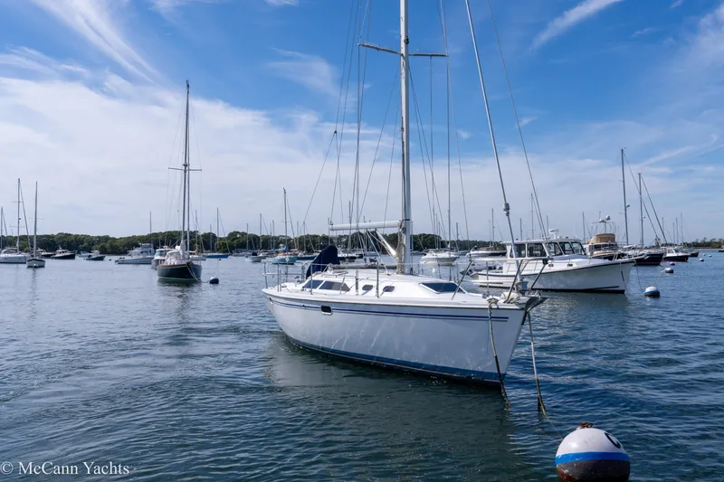 Slide: The Image of Sailboats anchored in a marina, featuring a 2003 Catalina 320 under a clear blue sky. - 2