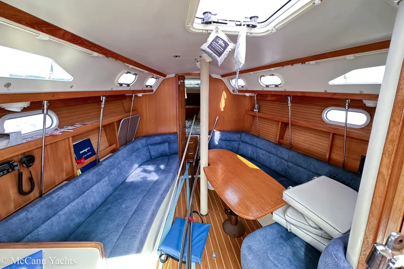 Slide: The Image of Interior of 2003 Catalina 320 sailboat with blue seating and wooden table. - 21