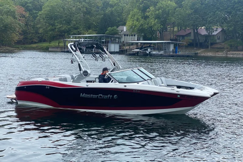 Slide: The Image of 2019 MasterCraft X24 boat on a lake with lush green surroundings. - 1
