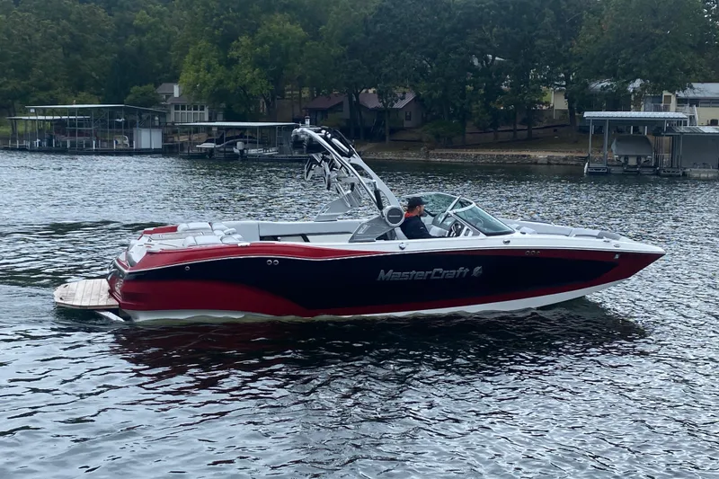 Slide: The Image of 2019 MasterCraft X24 boat cruising on a lake with scenic background. - 2