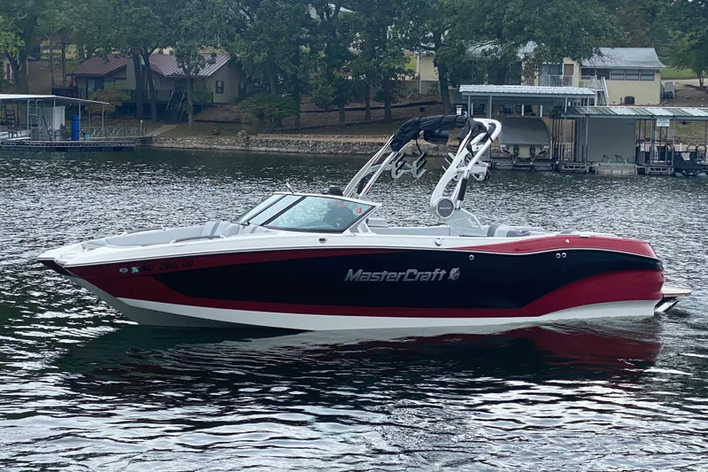 Slide: The Image of 2019 MasterCraft X24 boat on a lake, surrounded by trees and docks. - 5
