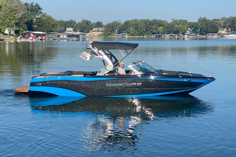 The Image of 2021 MasterCraft XT25 boat on a calm lake with scenic background. - 1