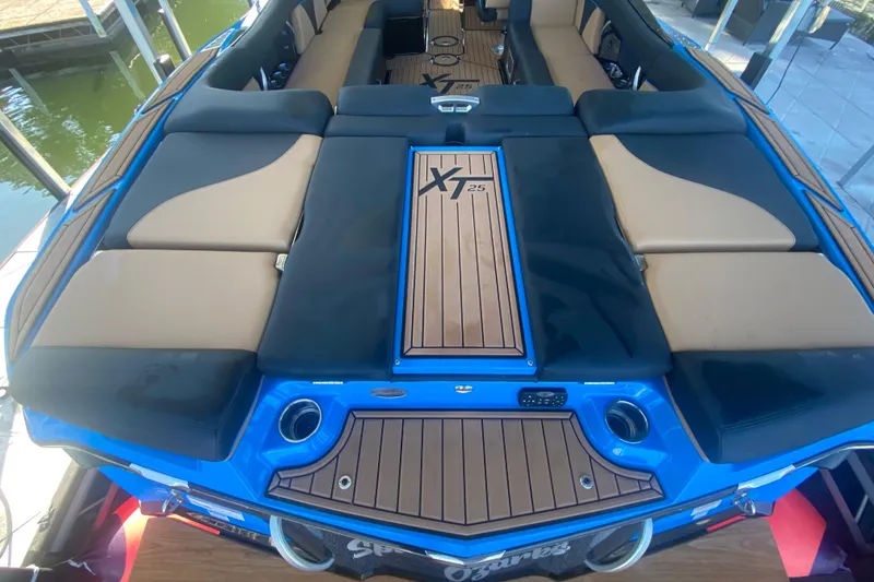 Slide: The Image of 2021 MasterCraft XT25 boat interior with cushioned seating and teak flooring. - 12