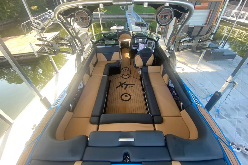 Slide: The Image of 2021 MasterCraft XT25 boat interior with tan and black seating, docked at a marina. - 13