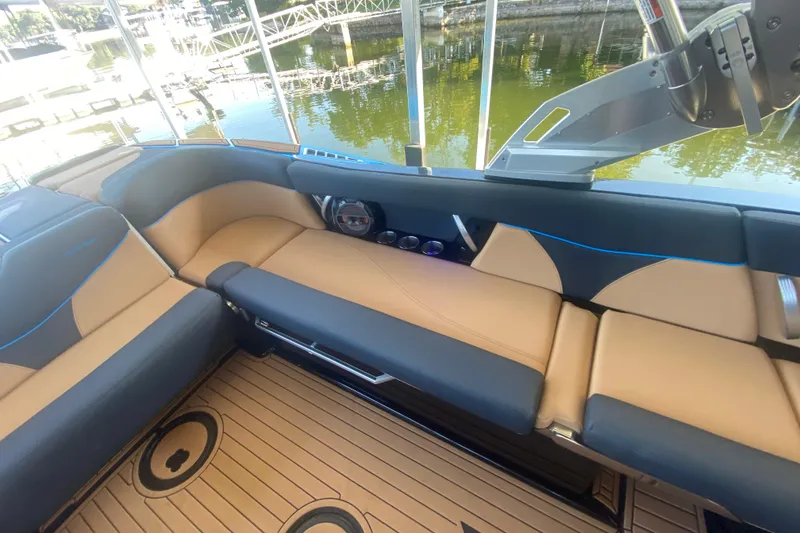 Slide: The Image of 2021 MasterCraft XT25 boat interior with tan and black seating, docked by the water. - 16