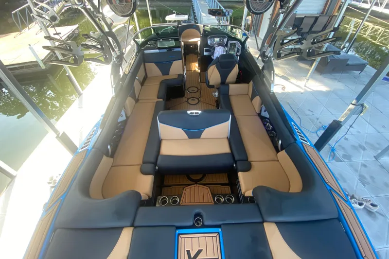 Slide: The Image of 2021 MasterCraft XT25 boat interior with tan and black seating, docked at a marina. - 17