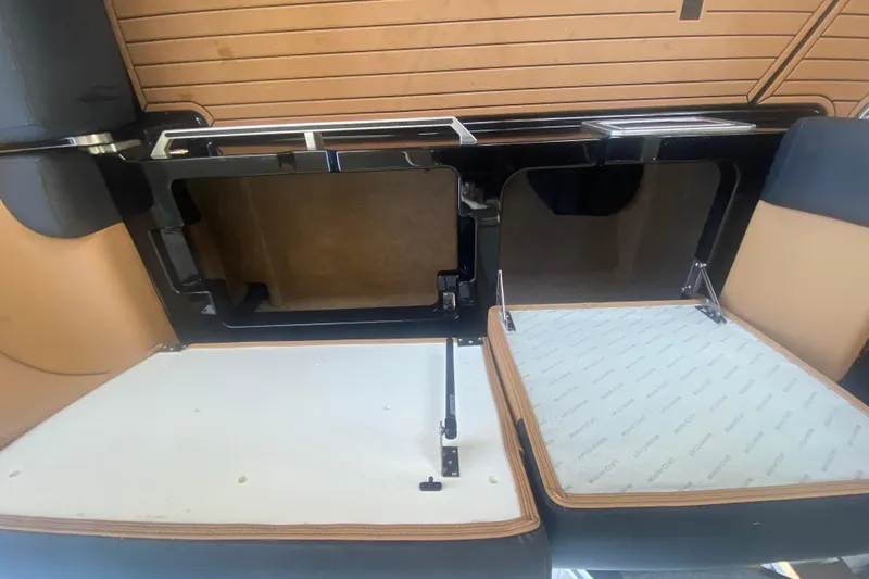 Slide: The Image of 2021 MasterCraft XT25 interior storage compartments with open lids, showcasing sleek design. - 19