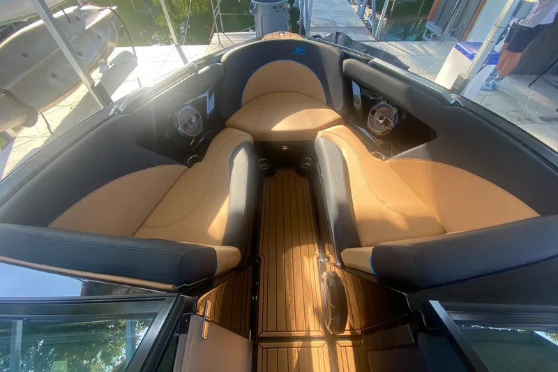 Slide: The Image of 2021 MasterCraft XT25 boat interior with tan and black seating, docked by the water. - 26