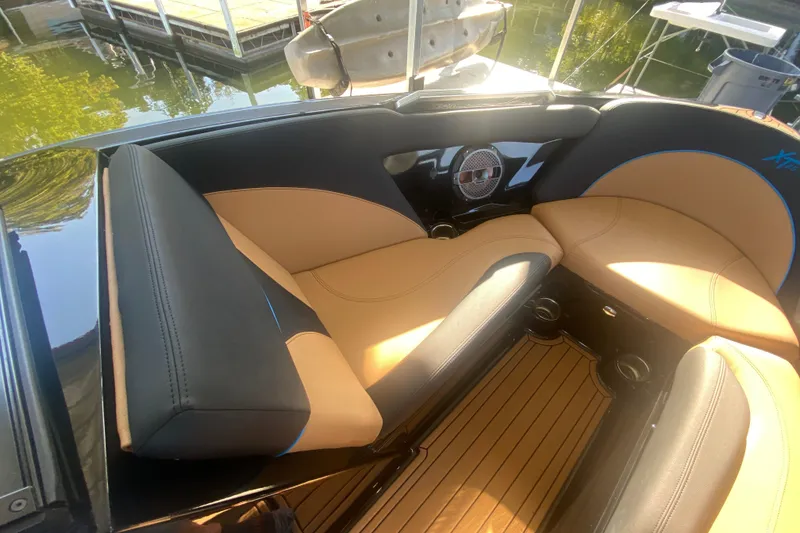 Slide: The Image of 2021 MasterCraft XT25 boat interior with tan and black seating, dockside view. - 27