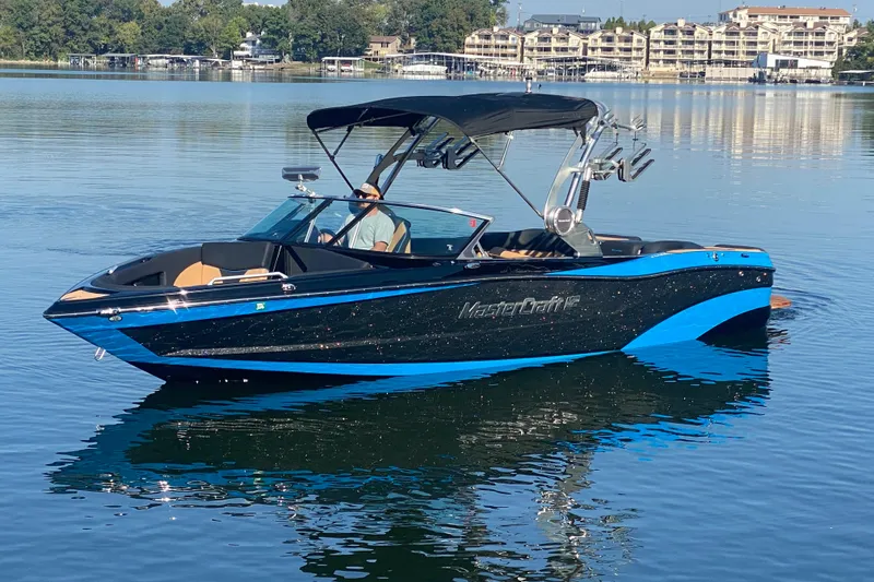 Slide: The Image of 2021 MasterCraft XT25 boat on calm lake with scenic background. - 3